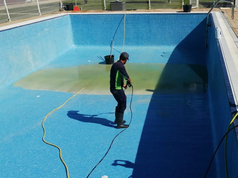 Labores de limpieza de la piscina con el vaso vacío. Operario de Paisajismolarioja limpiando una piscina.